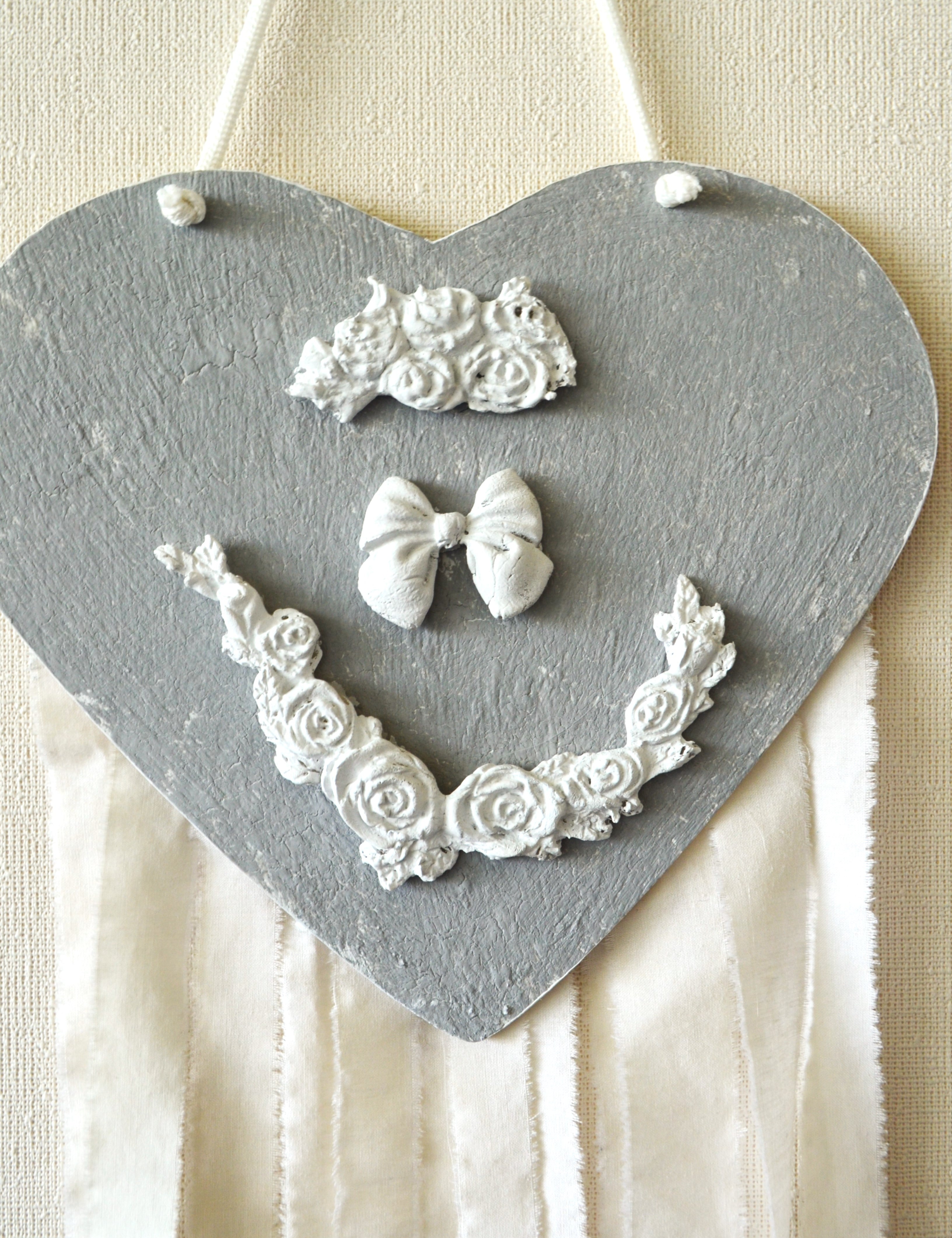 Detalle de adorno de pared infantil corazón gris estilo romántico con adornos en cerámicas y tiras de algodón exclusivo Lily Garden & deco