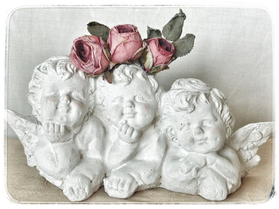 Figura religiosa que muestra  3 querubines decorados con flores preservadas Lily Garden & deco